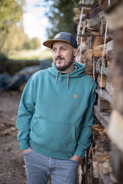 Benjamin Schey lehnt an einem Stapel Holz